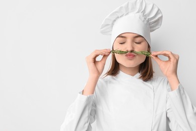 Photo of Professional chef with rosemary having fun on light background. Space for text