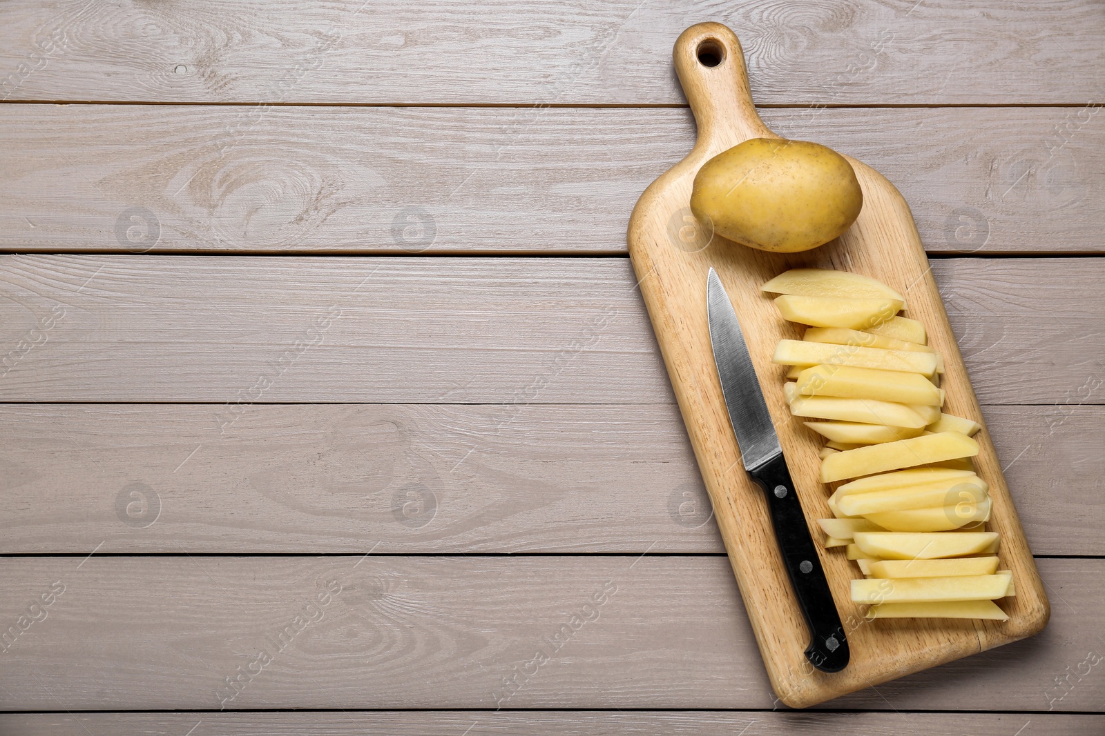 Photo of Whole and cut raw potatoes on wooden table, top view. Space for text