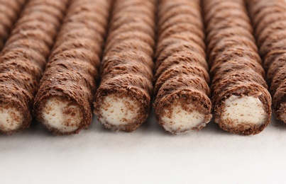 Delicious chocolate wafer rolls on white background, closeup. Sweet food