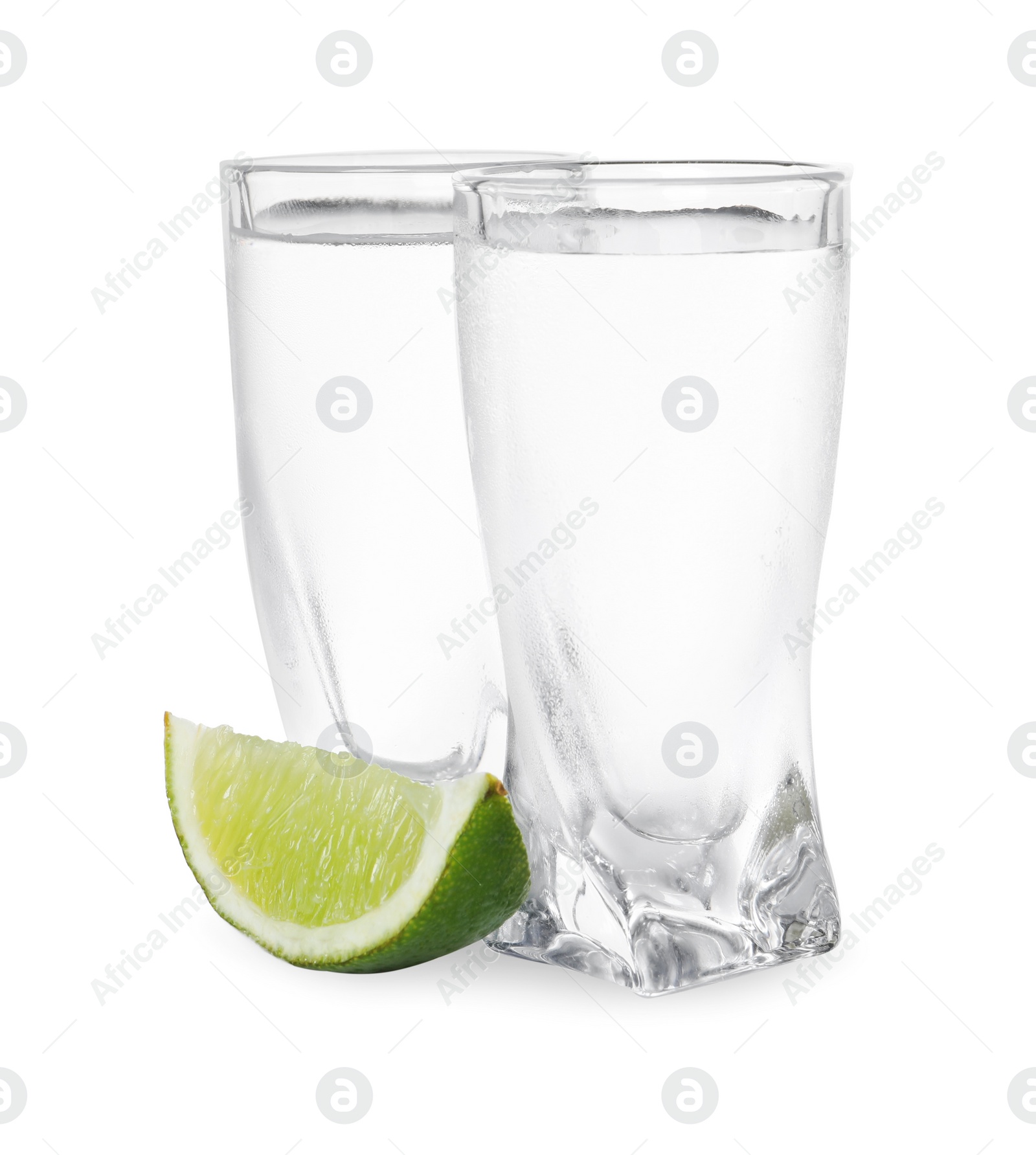 Photo of Shot glasses of vodka with lime slice on white background