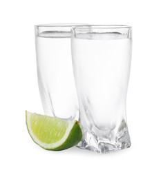 Shot glasses of vodka with lime slice on white background
