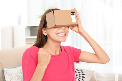 Young woman using cardboard virtual reality headset at home