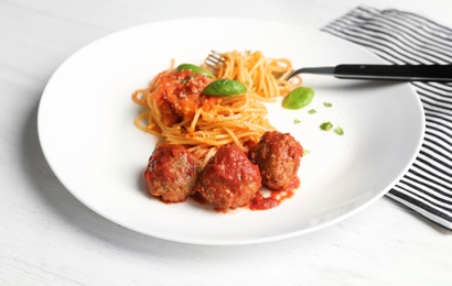 Photo of Delicious pasta with meatballs and tomato sauce on wooden background