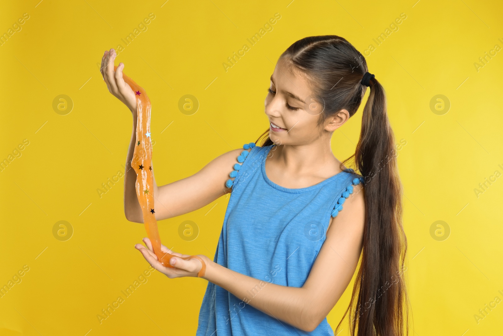 Photo of Preteen girl with slime on yellow background