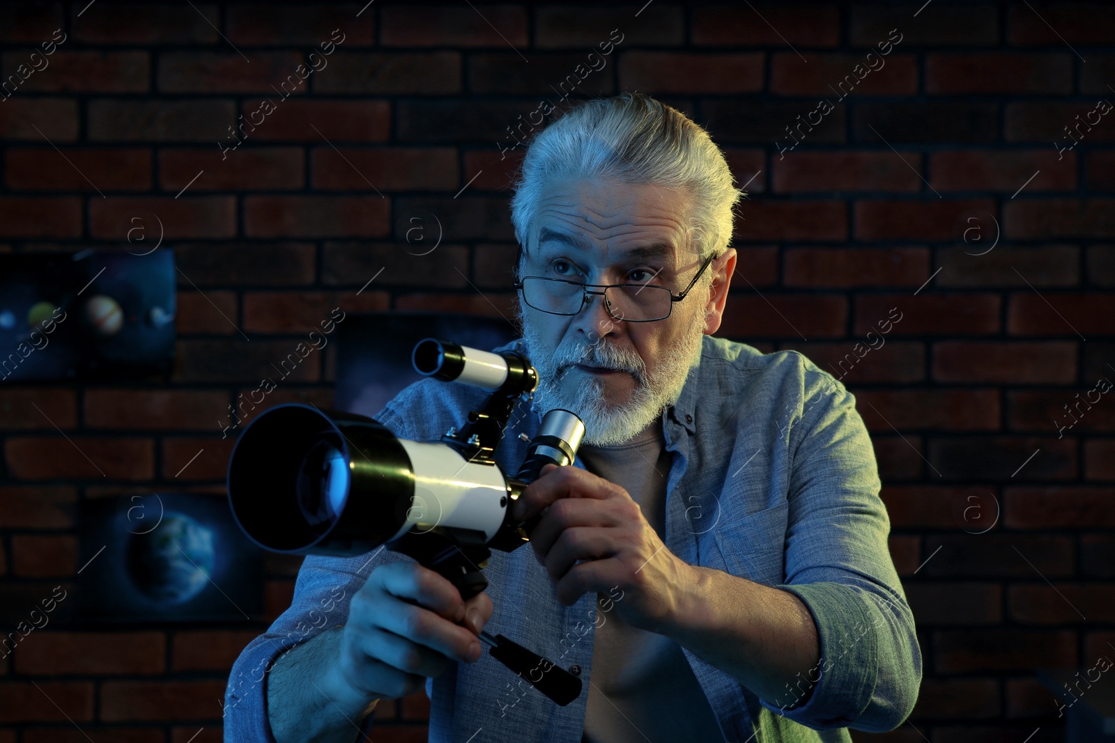 Photo of Senior man using telescope to look at stars in room