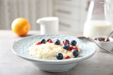 Photo of Creamy rice pudding with red currant and blueberries in bowl on table