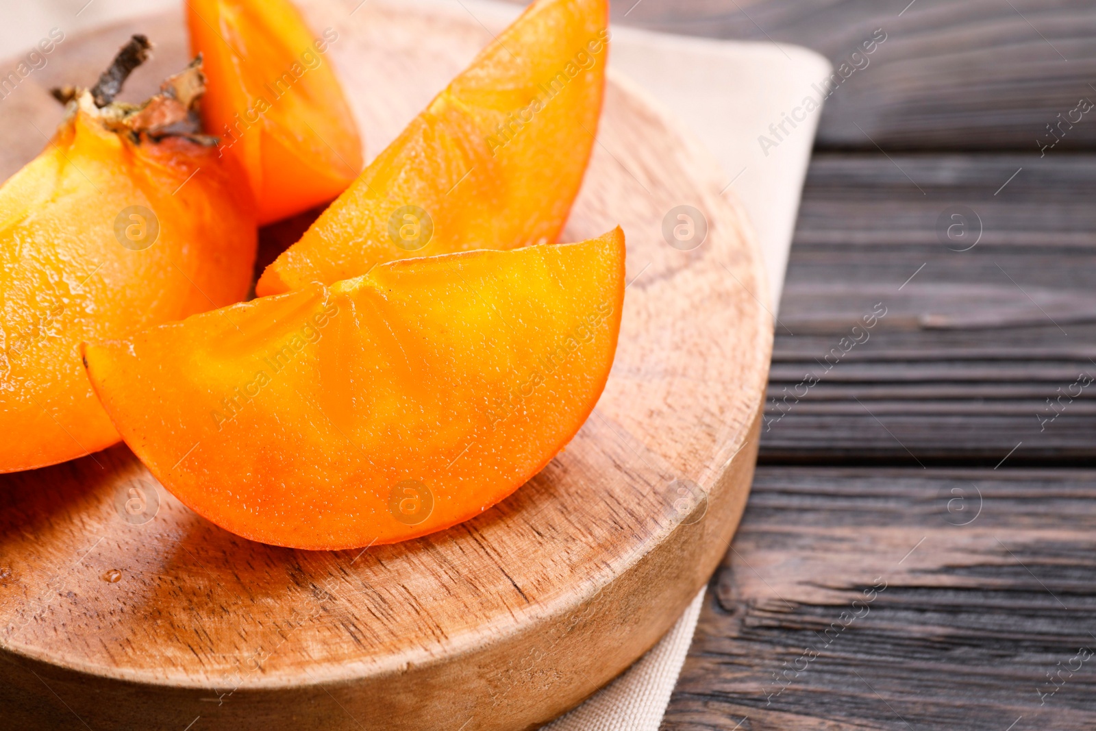 Photo of Pieces of delicious persimmons on wooden table, closeup. Space for text