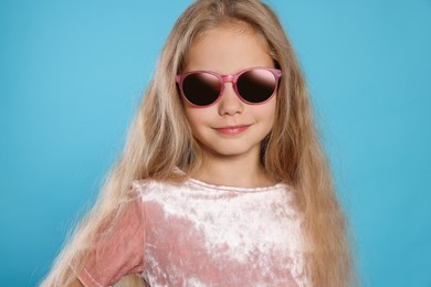 Photo of Girl in stylish sunglasses on light blue background