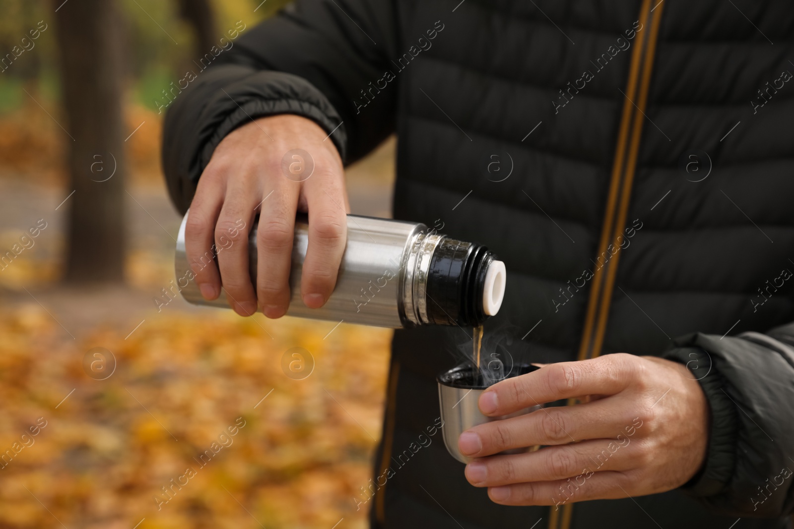 Photo of Man pouring drink from thermos into cap outdoors, closeup