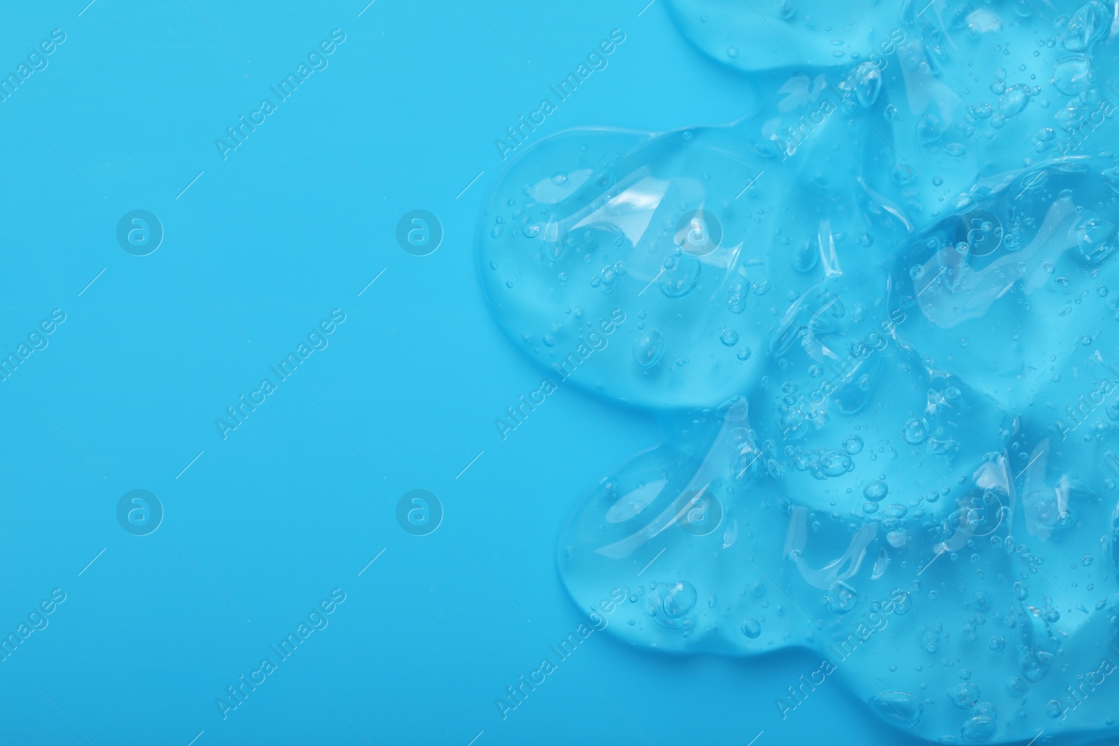 Photo of Pure transparent cosmetic gel on light blue background, top view