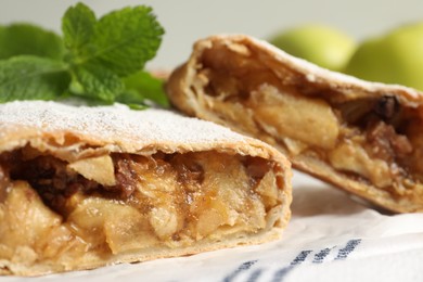Photo of Delicious strudel with apples, nuts and powdered sugar on table, closeup