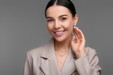 Photo of Beautiful young woman with elegant jewelry on dark grey background