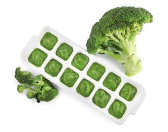 Photo of Broccoli puree in ice cube tray and ingredients on white background, top view. Ready for freezing