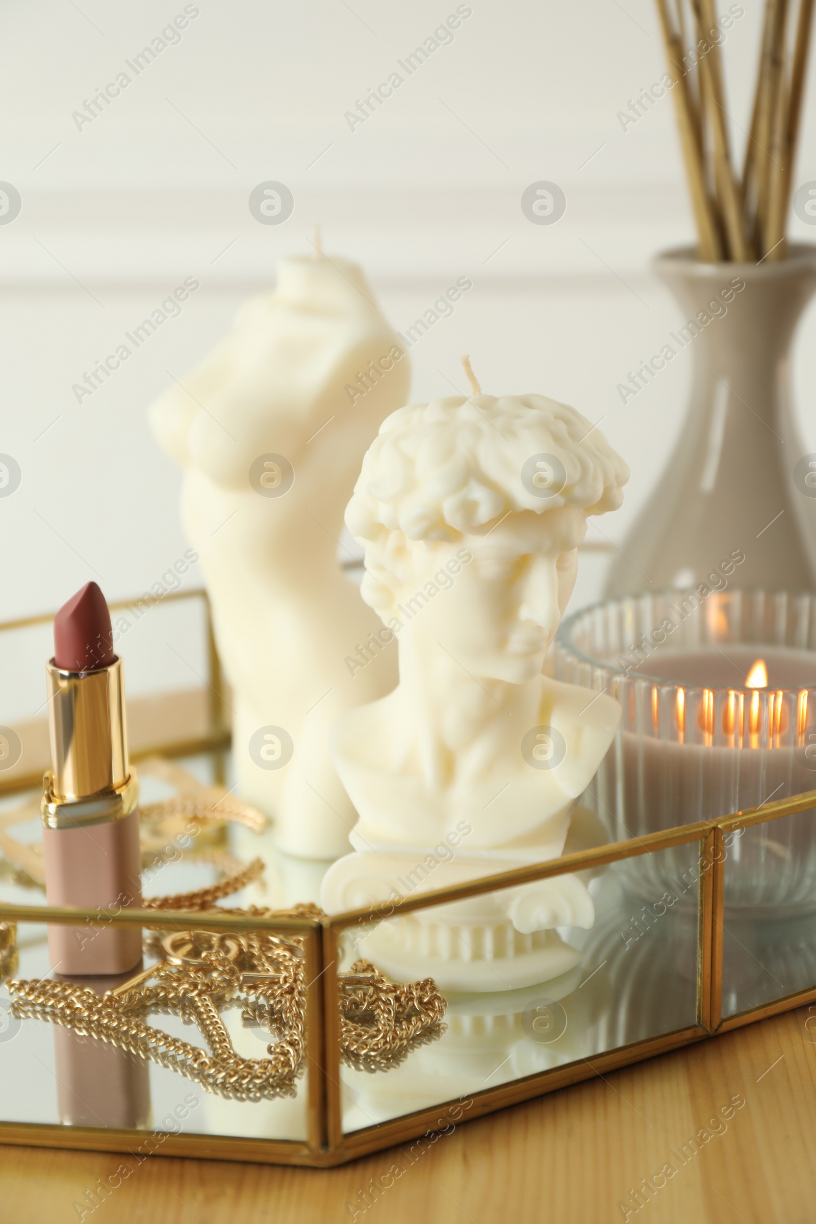 Photo of David bust and female body shaped candles on wooden table. Stylish decor