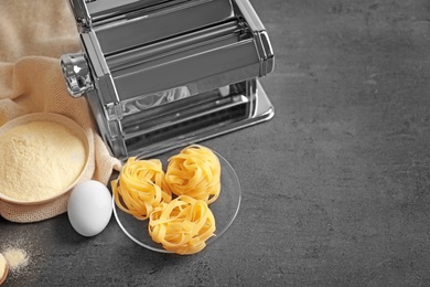 Photo of Pasta machine and products on grey background