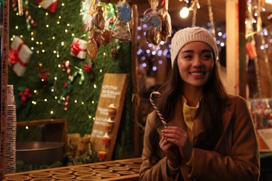 Photo of Young woman spending time at Christmas fair, space for text