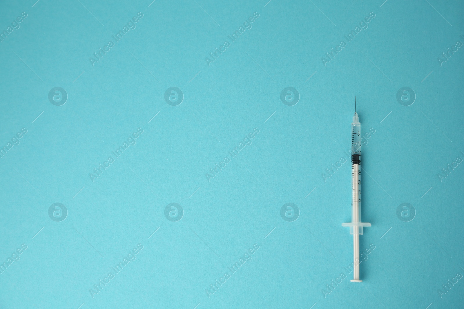Photo of Medical syringe on light blue background, top view. Space for text