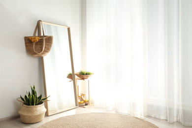 Photo of Large mirror with wooden frame near window in light room
