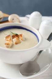Delicious cream soup with croutons in bowl on table, closeup