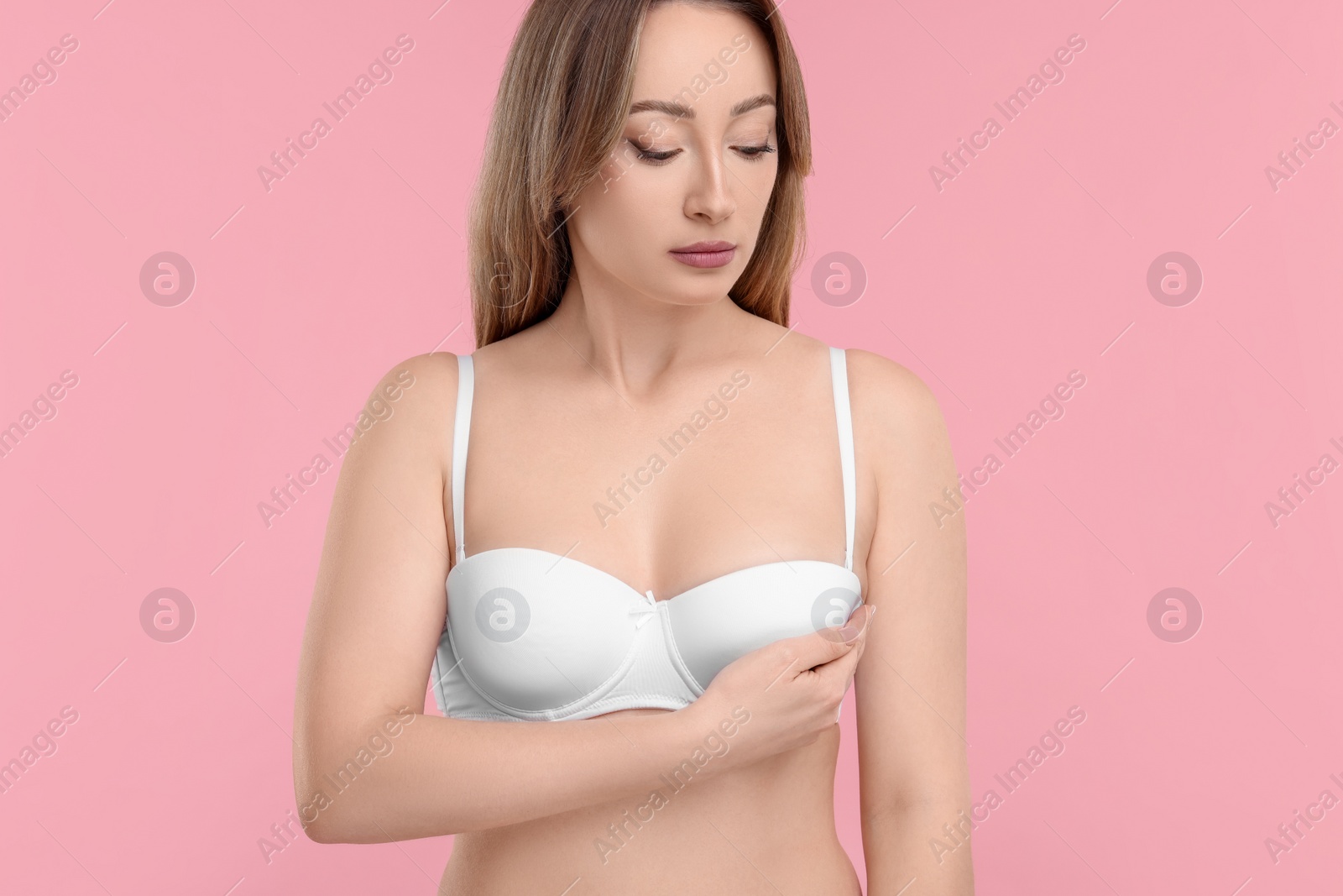 Photo of Mammology. Young woman doing breast self-examination on pink background