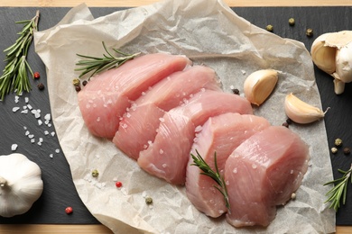 Photo of Cut raw turkey fillet and ingredients on board, top view