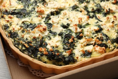 Photo of Delicious homemade spinach quiche in carton box, closeup