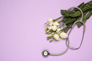 Stethoscope and beautiful flowers on light violet background, flat lay with space for text. Happy Doctor's Day