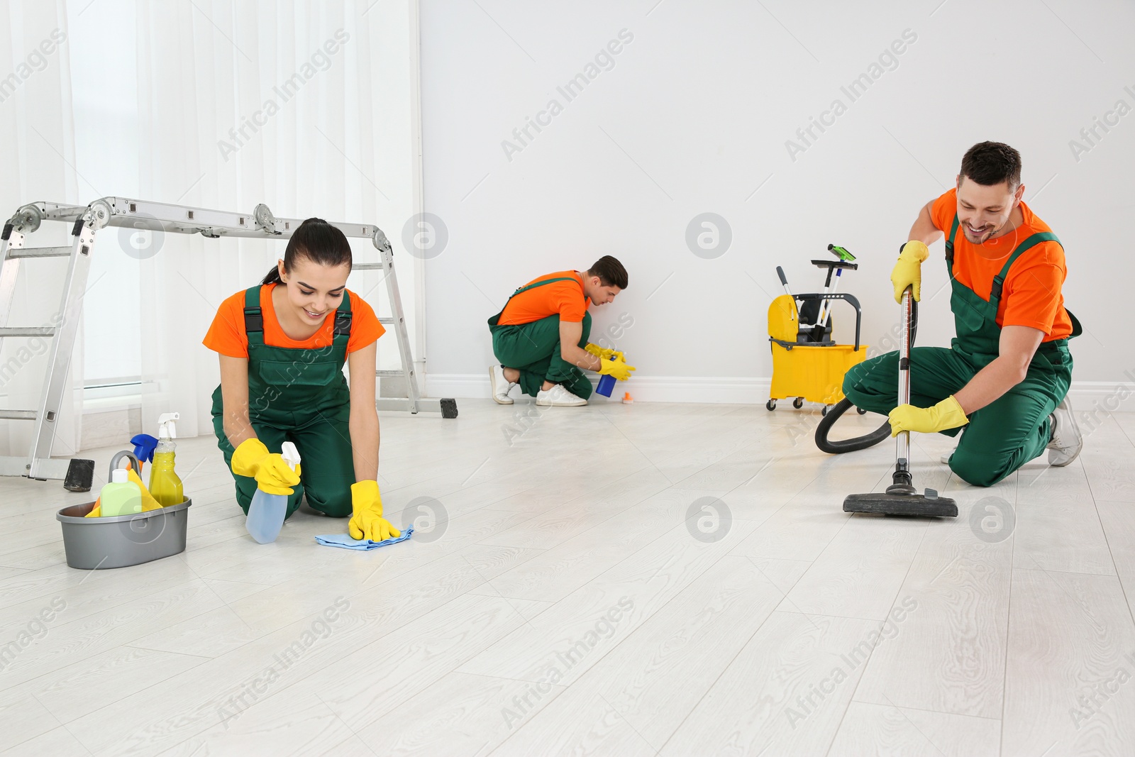 Photo of Team of professional janitors cleaning room after renovation