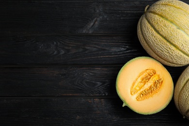 Photo of Tasty fresh melons on black wooden table, flat lay. Space for text