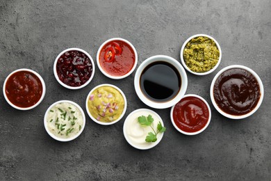 Photo of Different tasty sauces in bowls on grey table, flat lay