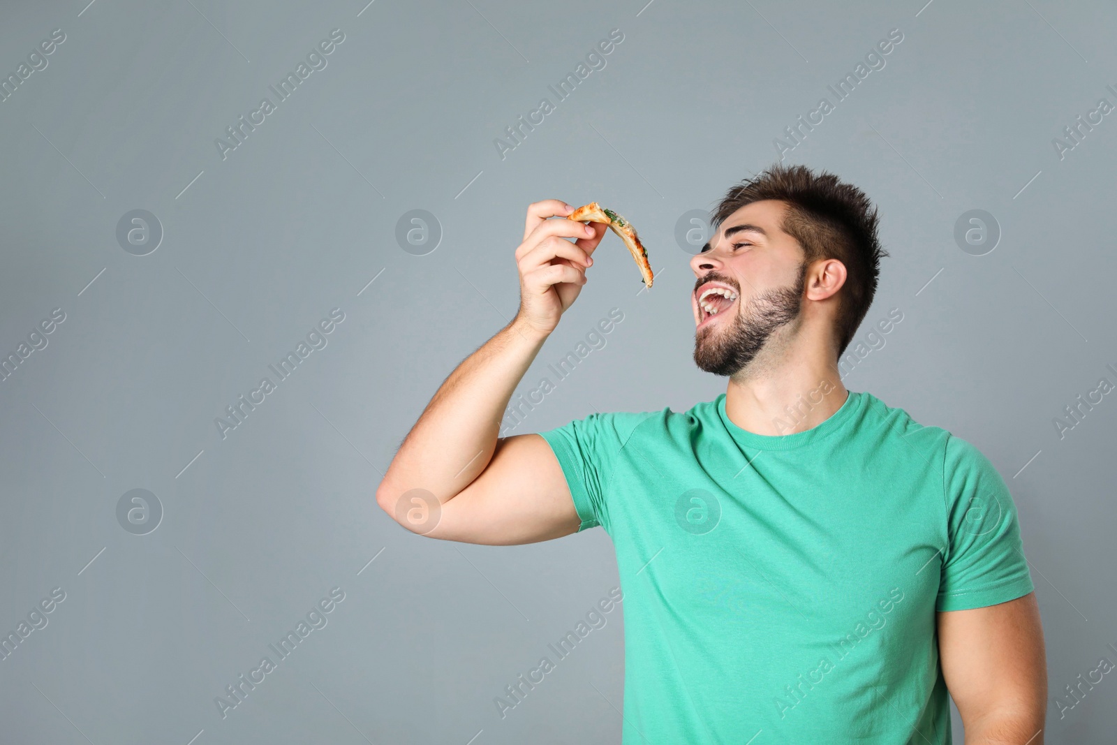 Photo of Handsome man with pizza on grey background, space for text