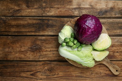 Photo of Different types of cabbage on wooden table, top view. Space for text
