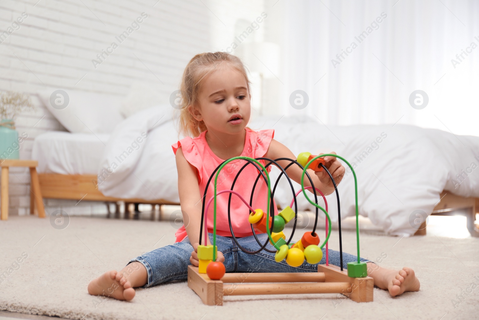 Photo of Cute child playing with bead maze on floor at home