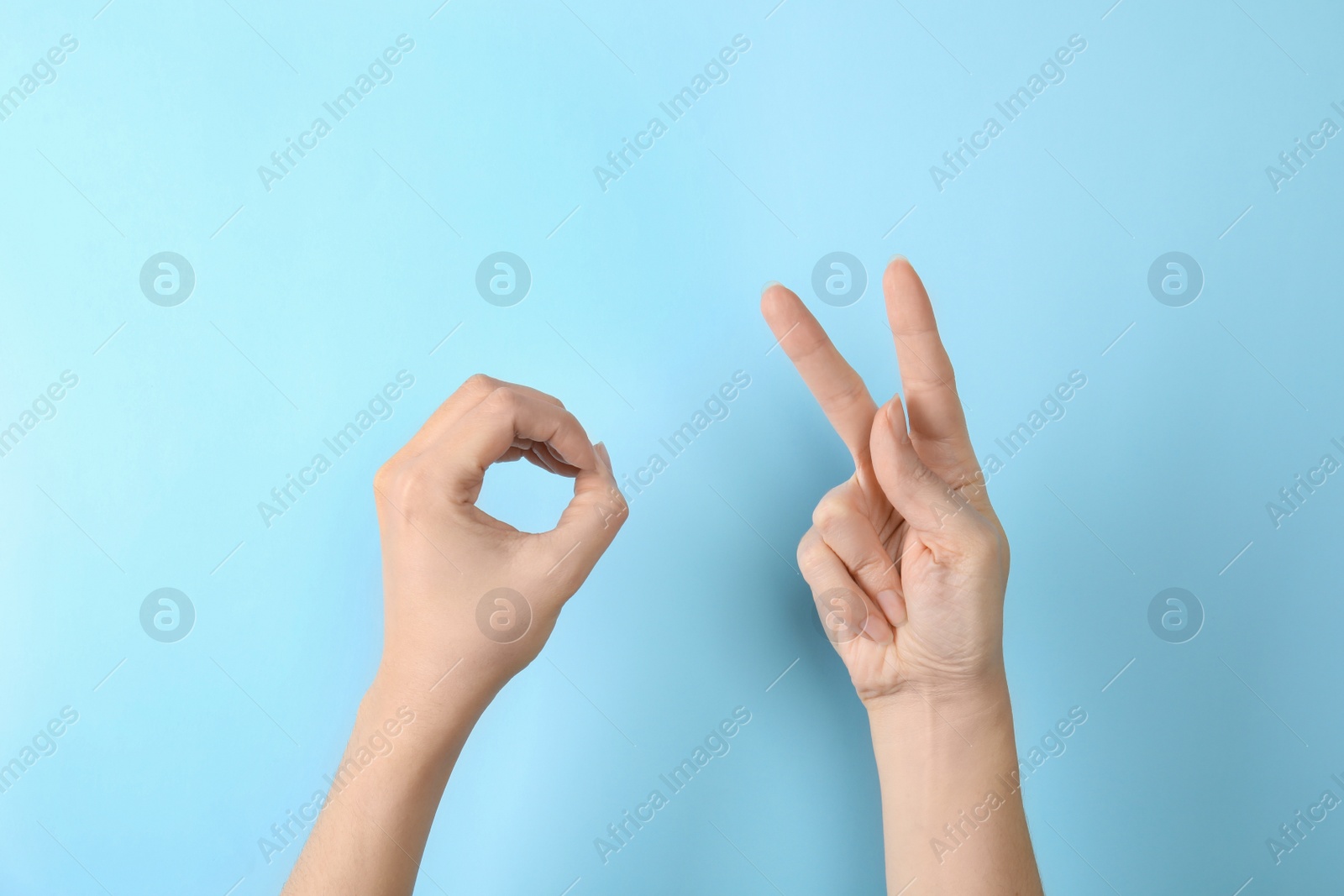 Photo of Woman showing word okay on color background, closeup. Sign language