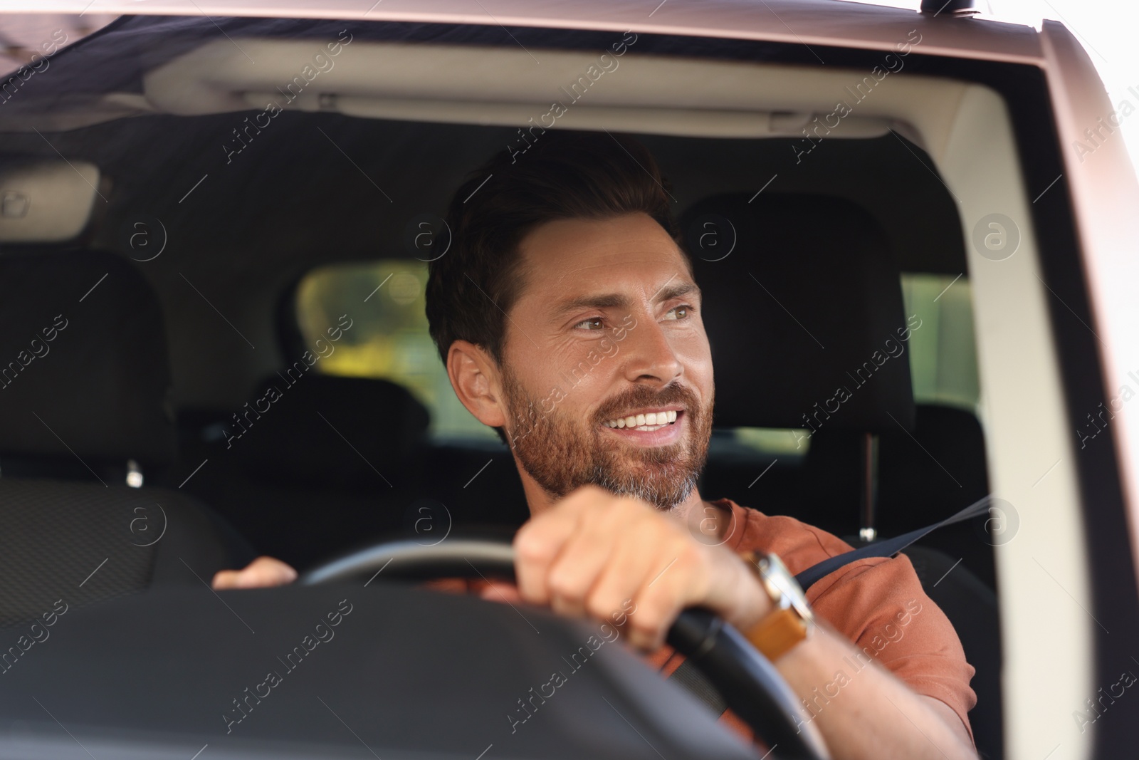 Photo of Enjoying trip. Happy bearded man driving car, view through windshield