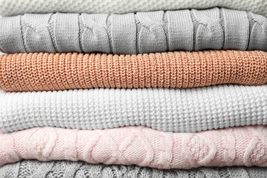 Photo of Stack of warm clothes as background, closeup. Autumn season