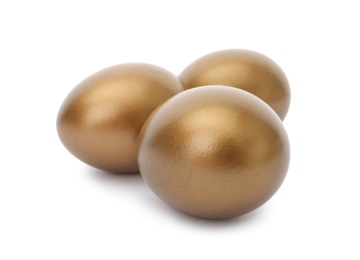 Photo of Three shiny golden eggs on white background