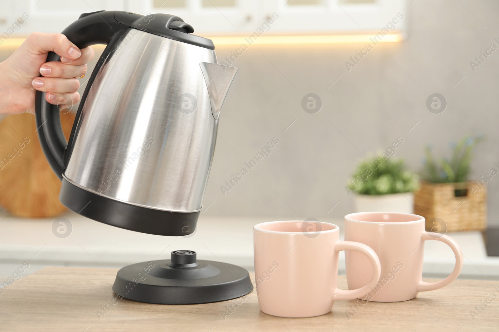 Photo of Woman with electric kettle in kitchen, closeup. Space for text