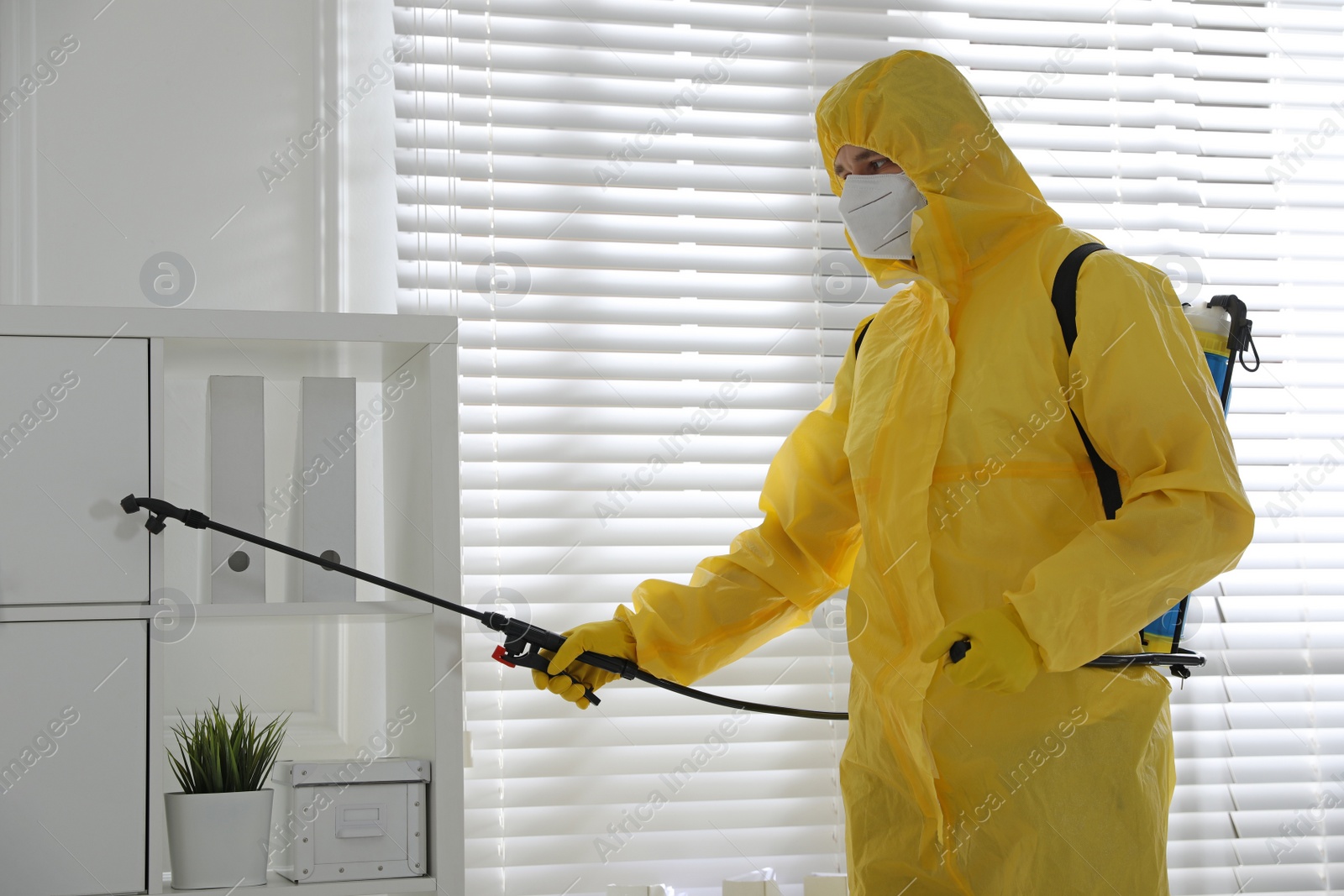 Photo of Man in protective suit sanitizing doctor's office. Medical disinfection