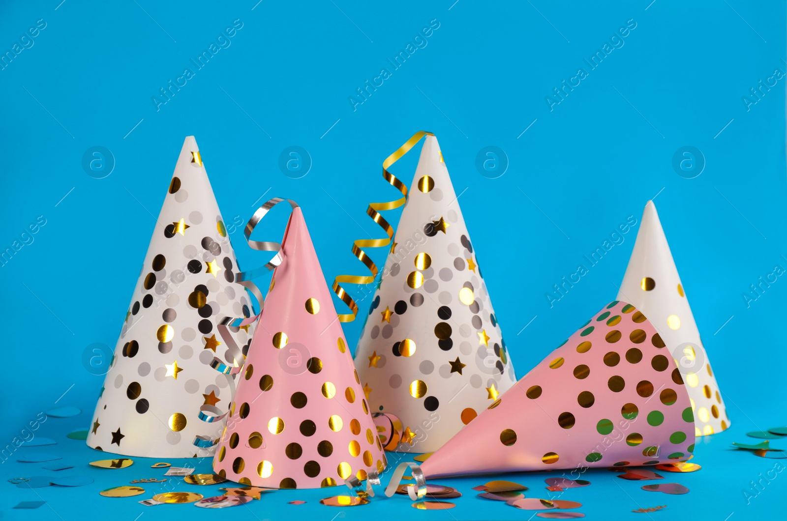 Photo of Colorful party hats and confetti on light blue background