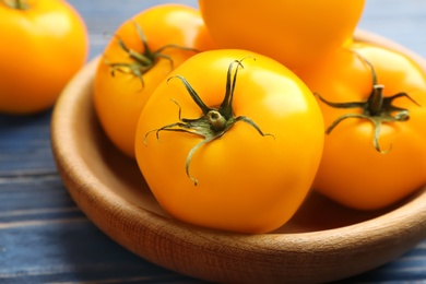 Photo of Ripe yellow tomatoes on wooden plate, closeup