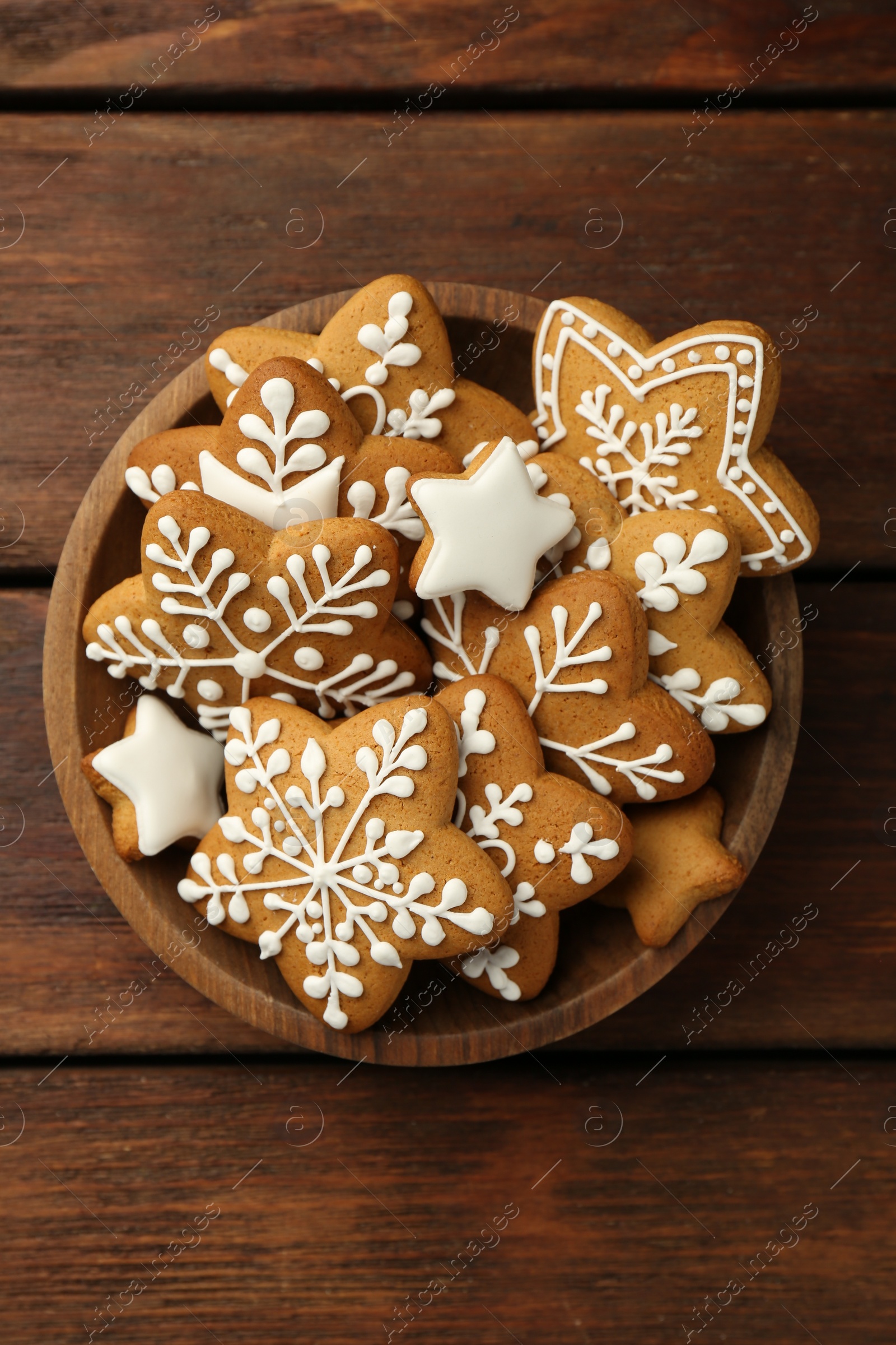 Photo of Tasty Christmas cookies with icing in bowl on wooden table, top view