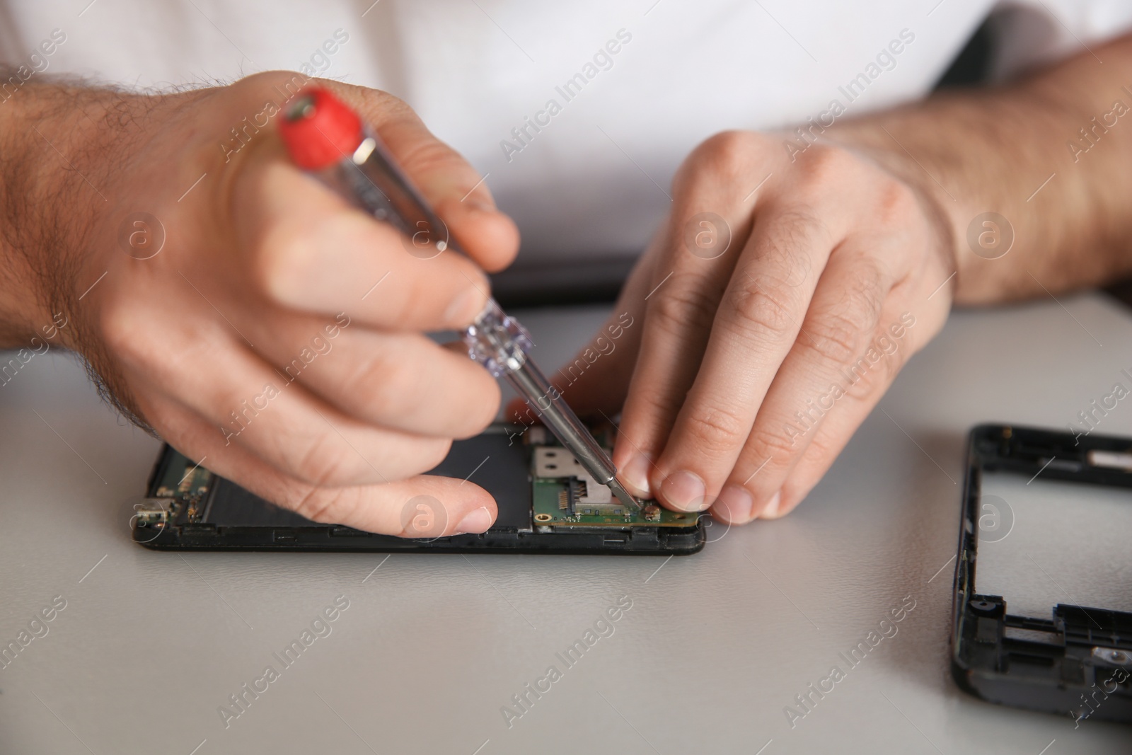 Photo of Technician repairing mobile phone at table, closeup