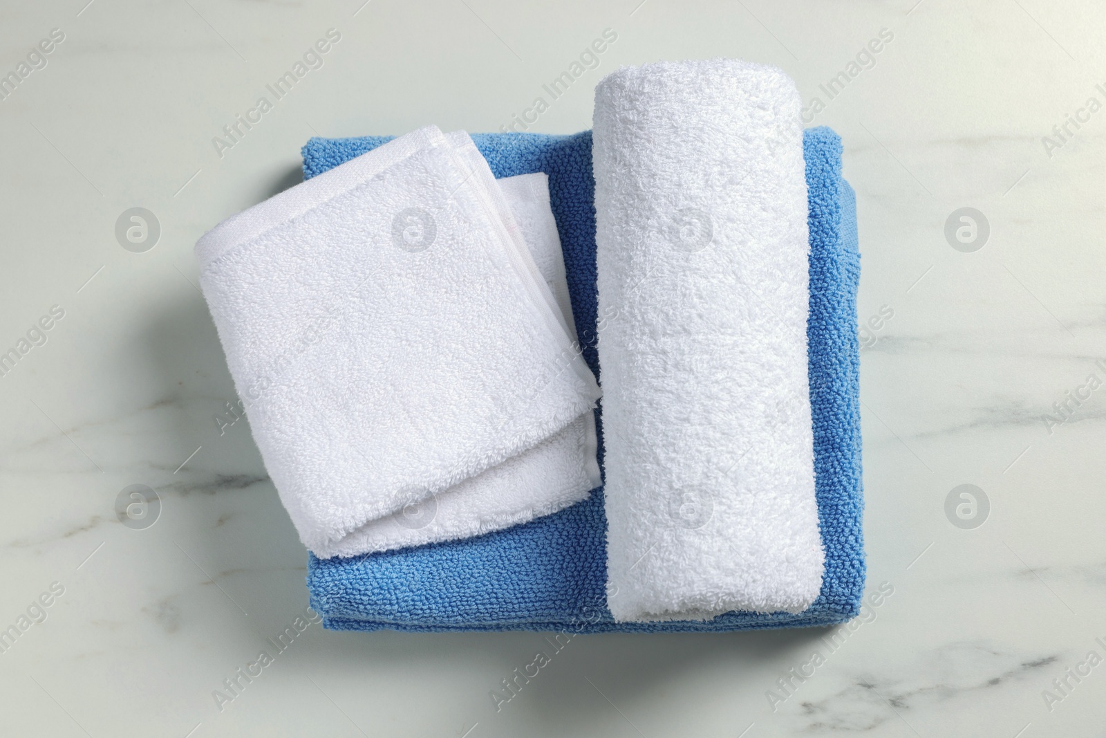 Photo of Clean folded towels on white marble table, top view