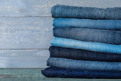 Photo of Stack of different jeans on blue wooden table