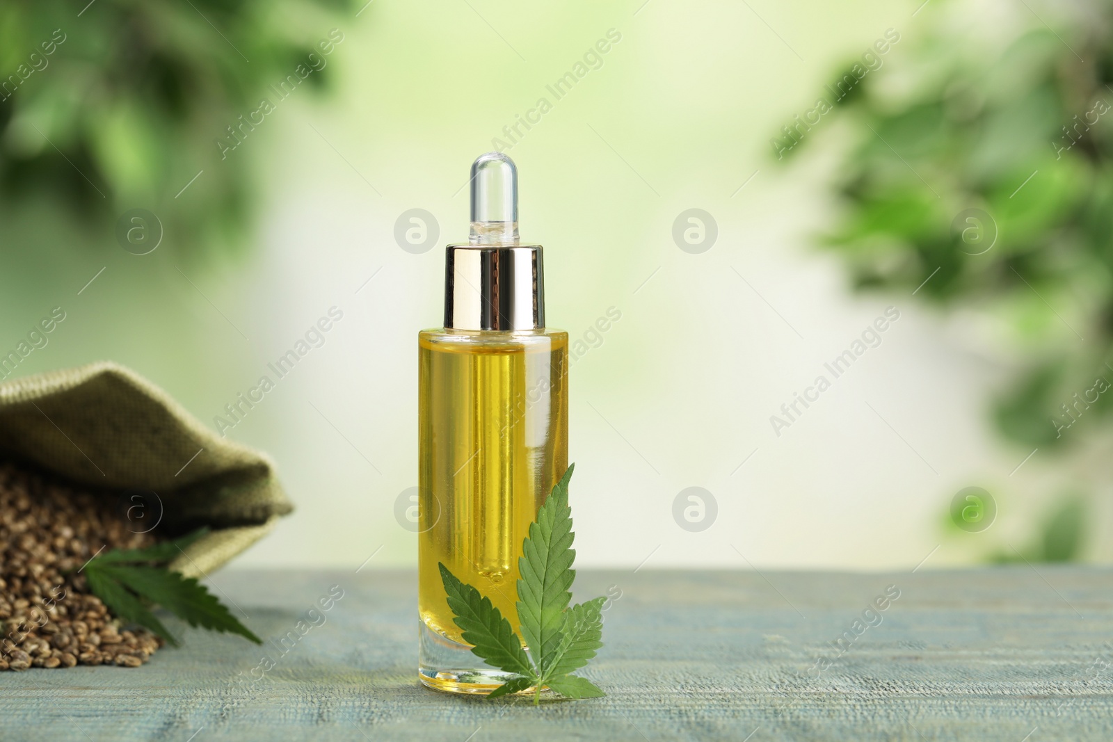 Photo of Hemp oil and leaf on wooden table against blurred background. Space for text