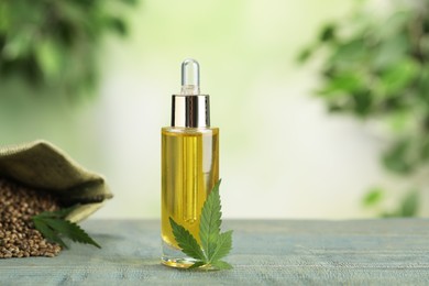 Photo of Hemp oil and leaf on wooden table against blurred background. Space for text