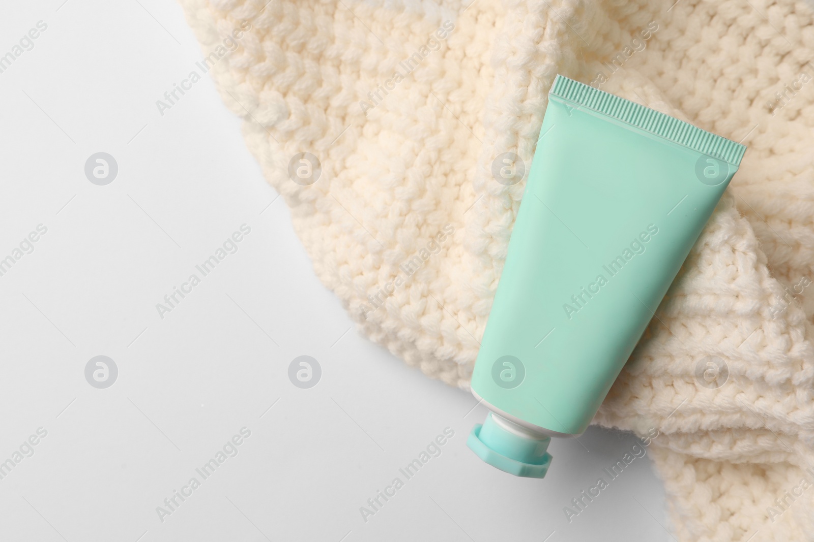 Winter skin care. Hand cream and knitted sweater on white background, top view. Space for text Photo of Winter skin care. Hand cream and knitted sweater on white background, top view. Space for text
