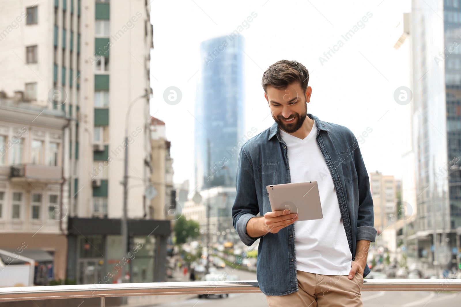 Photo of Handsome man working with tablet on city street