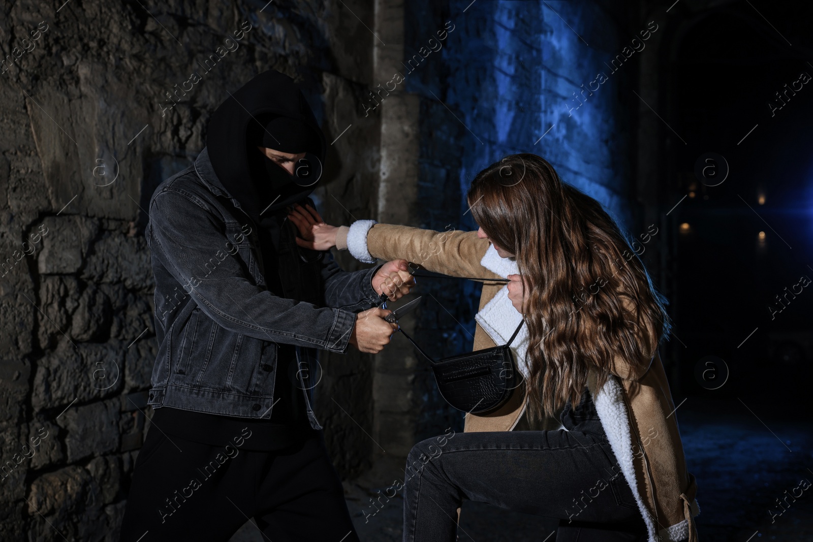 Photo of Woman fighting with thief while he trying to steal her bag in alley at night. Self defense concept